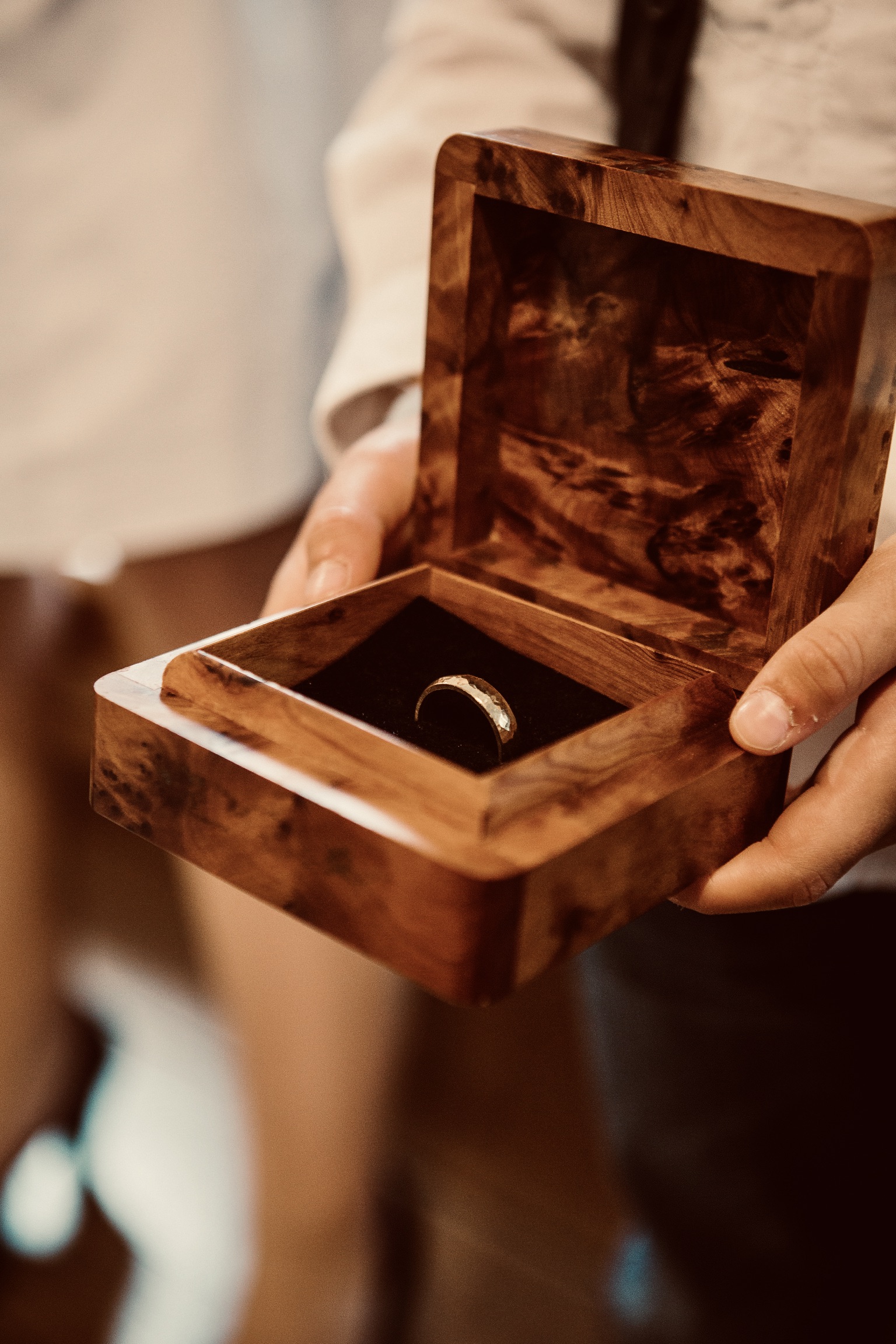 Hände mit einem Ring in einer Holzschatulle
